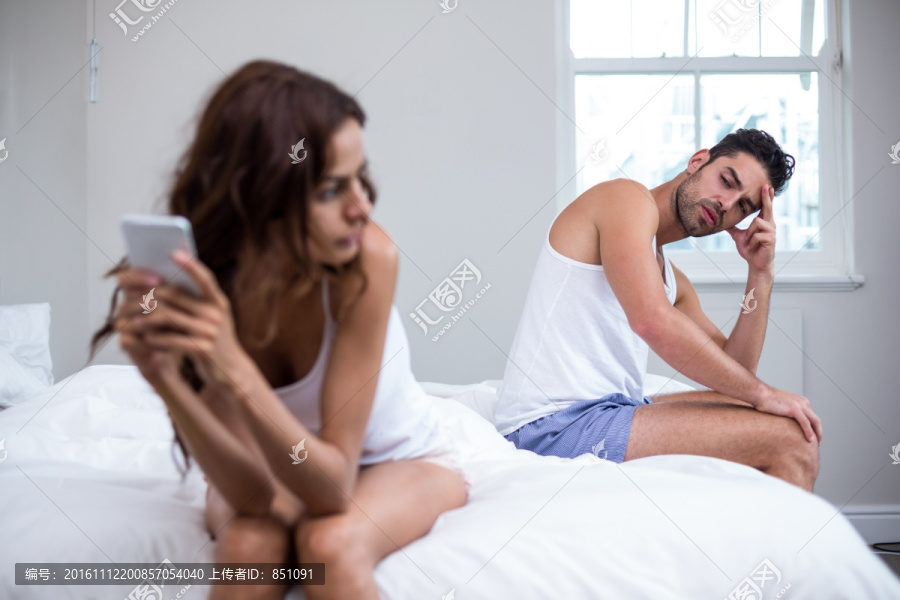 坐在床上使用手机的女人