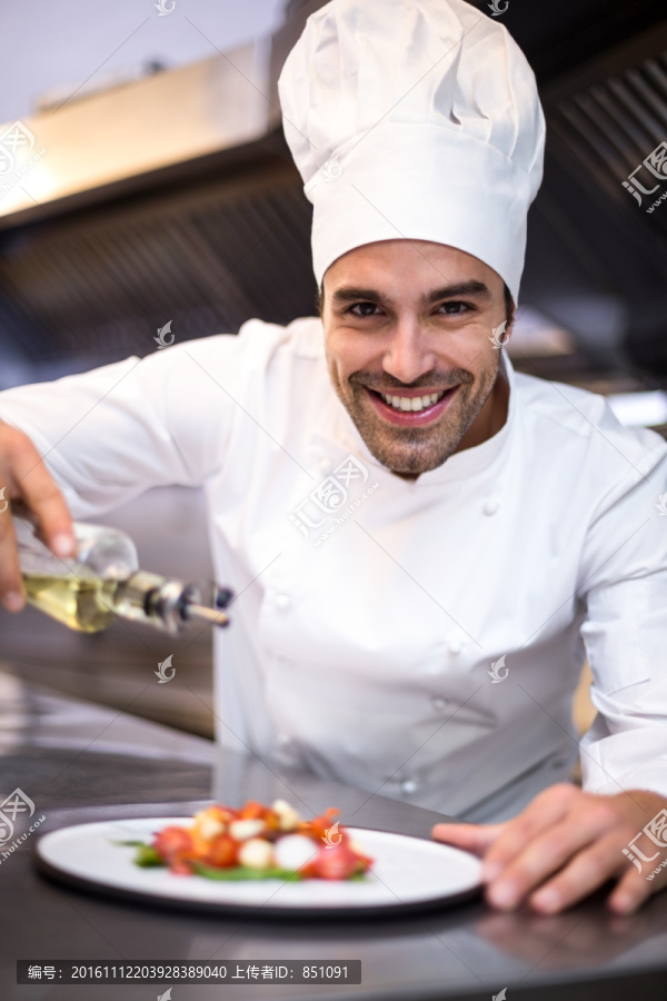 在菜肴中浇橄榄油的男厨师