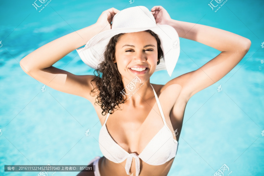 幸福的女人戴着白帽子在泳池边