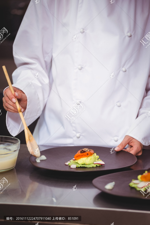 厨师把酱涂在盘子上