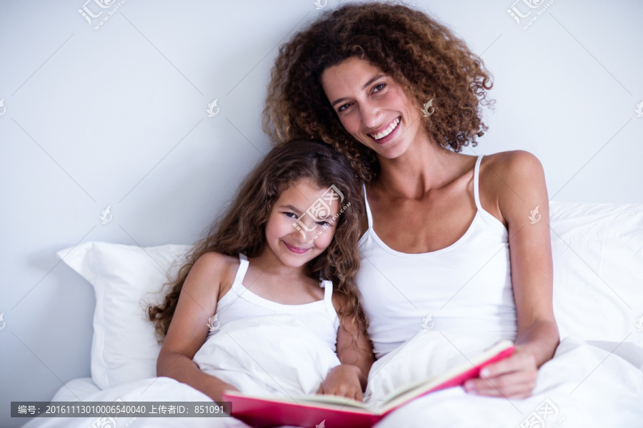 坐在床上看书的一对母女