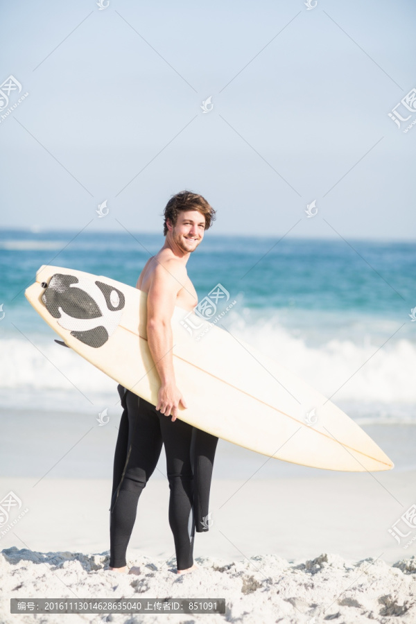 在海边拿着冲浪板的男人
