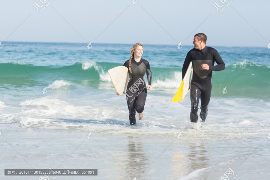 拿着冲浪板奔跑的夫妇