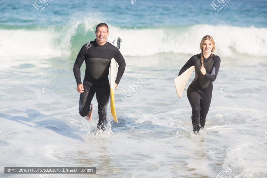拿着冲浪板冲向大海的夫妇