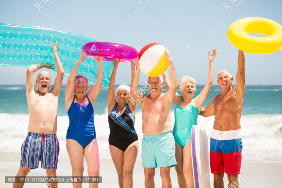 拿着游泳圈站在沙滩上的老人们