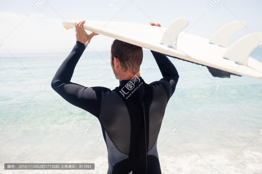 拿着冲浪板放在头顶上的男人