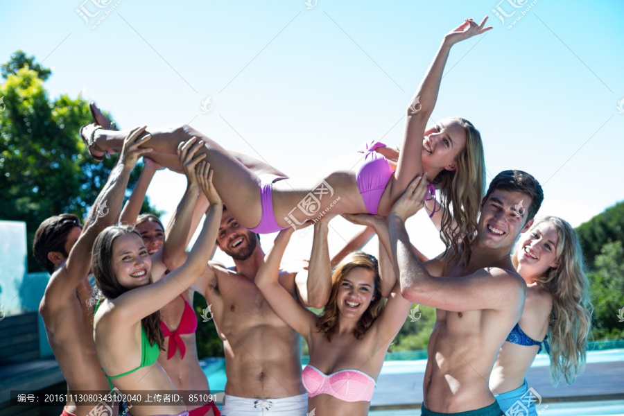 一群朋友在游泳池边举起一个女人