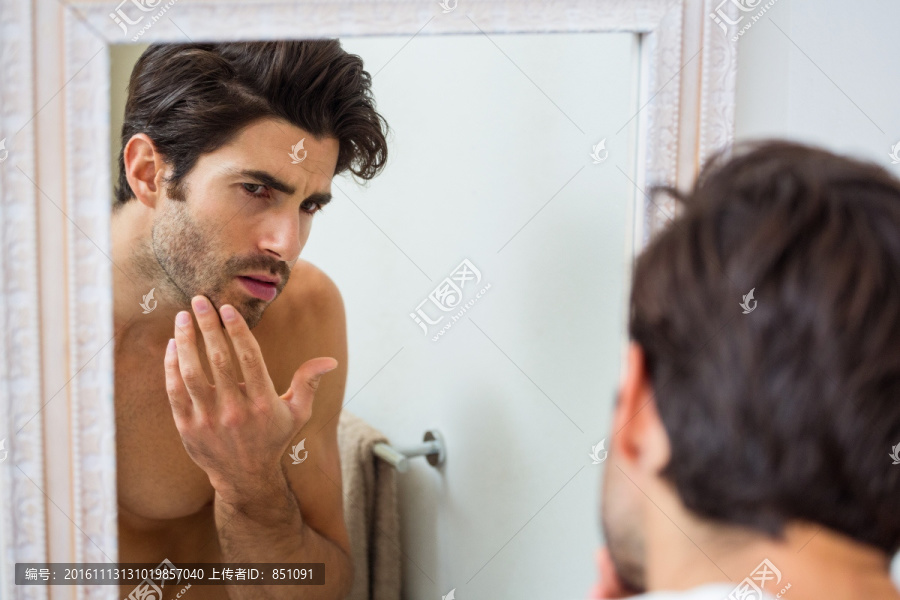 在浴室里检查下巴胡子的男人