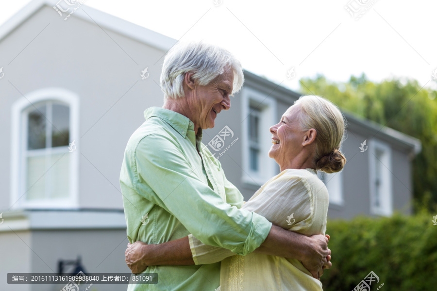 微笑的老夫妇拥抱在院子里