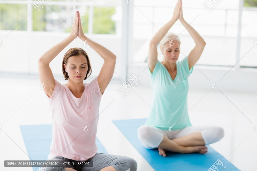 坐在瑜伽垫上举起双臂的女人