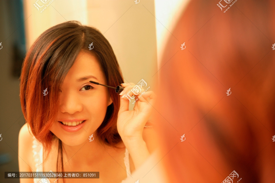 在照镜子涂睫毛膏的女人