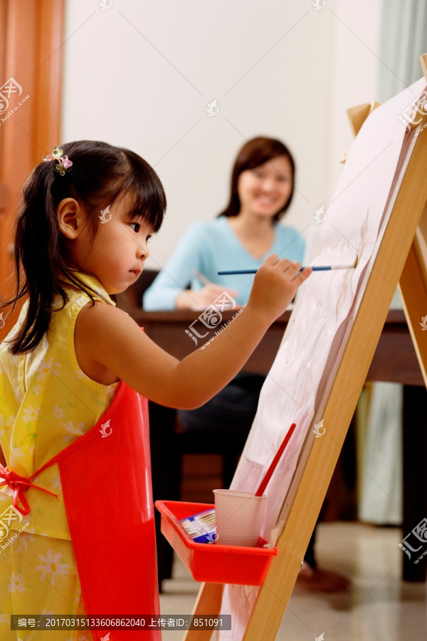 年轻的女孩画在画架上