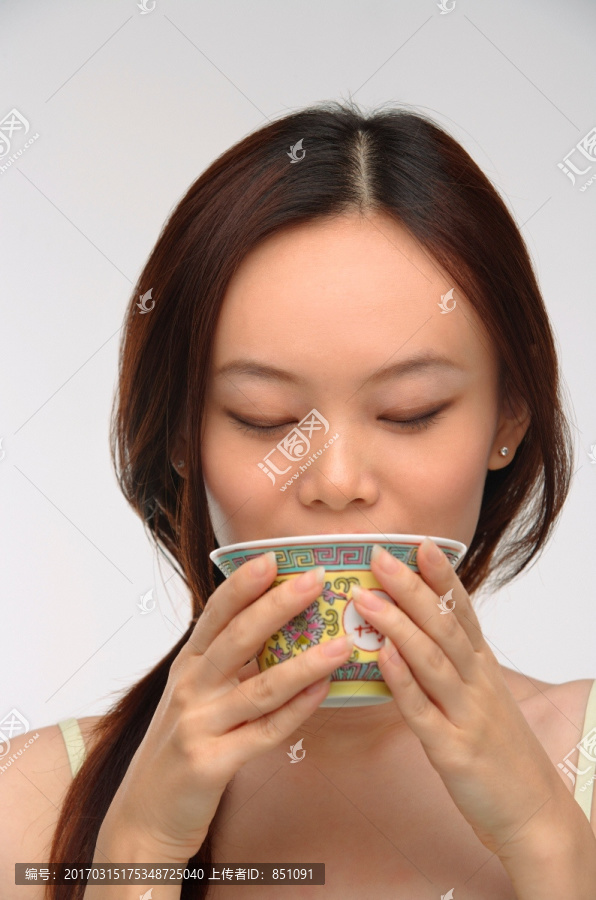 从传统茶杯喝茶的年轻女子