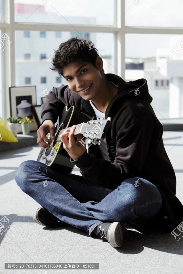 年轻人坐在地上弹吉他