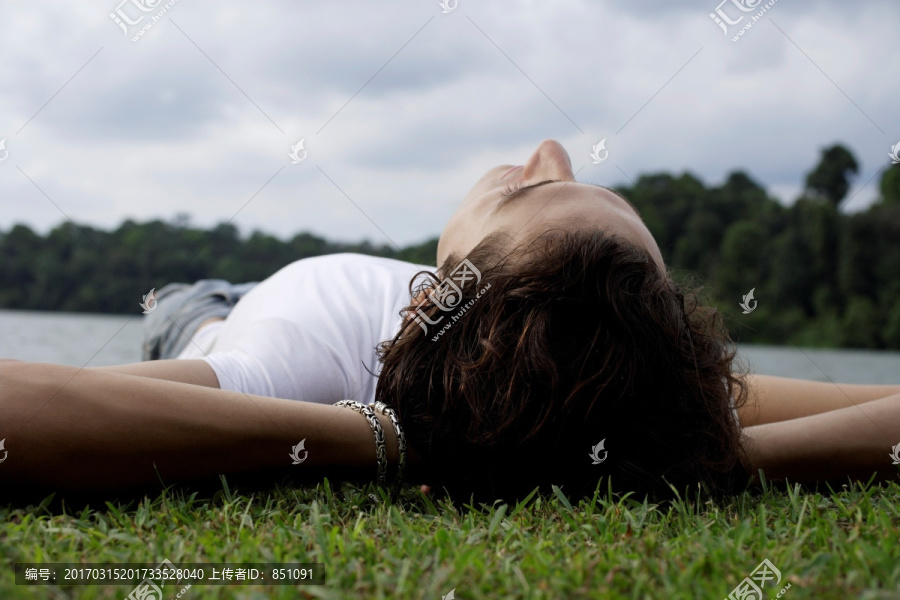 躺在湖边的草地上的年轻人