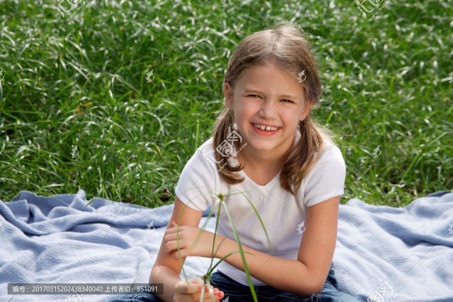 小女孩坐在草地上的毯子上