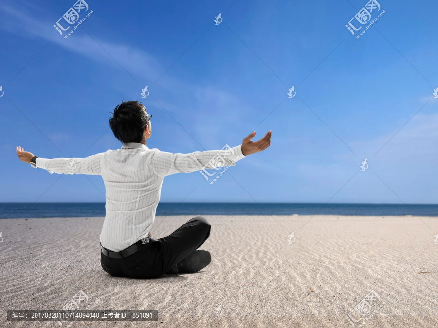 盘腿坐在沙滩上的男人