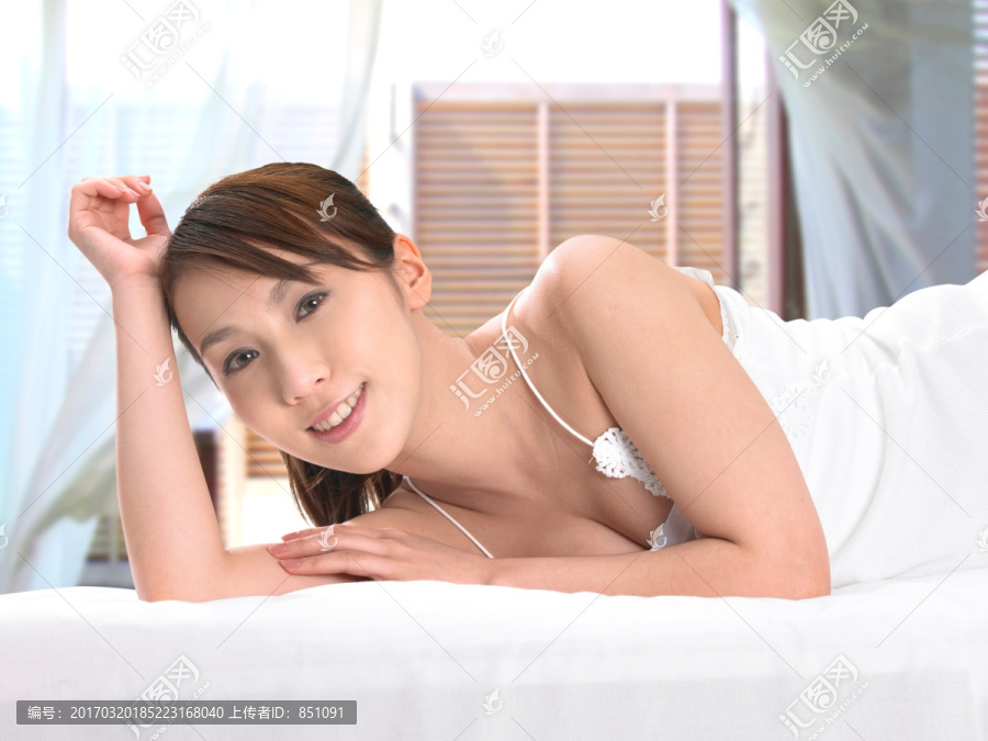 微笑的女人趴在床上