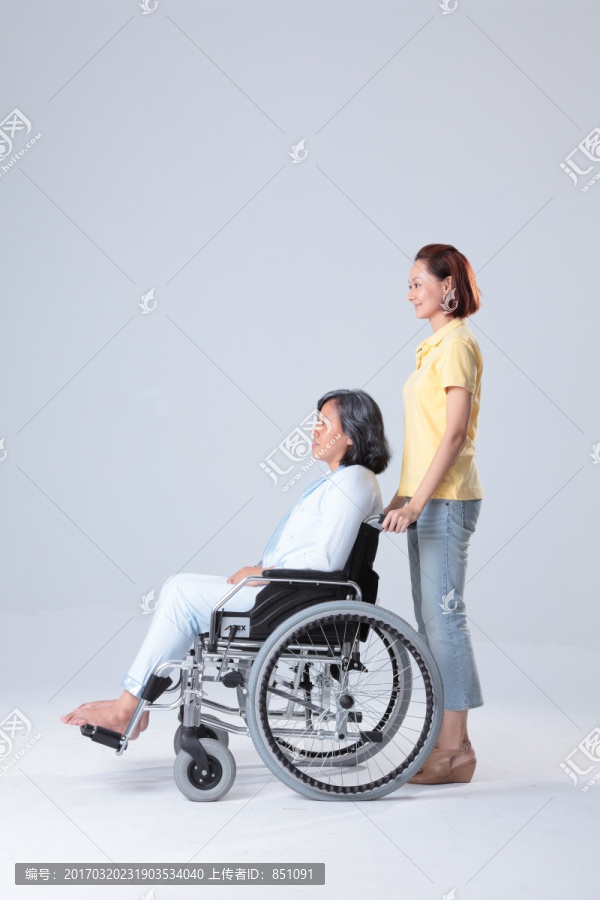 女人推着坐轮椅的母亲
