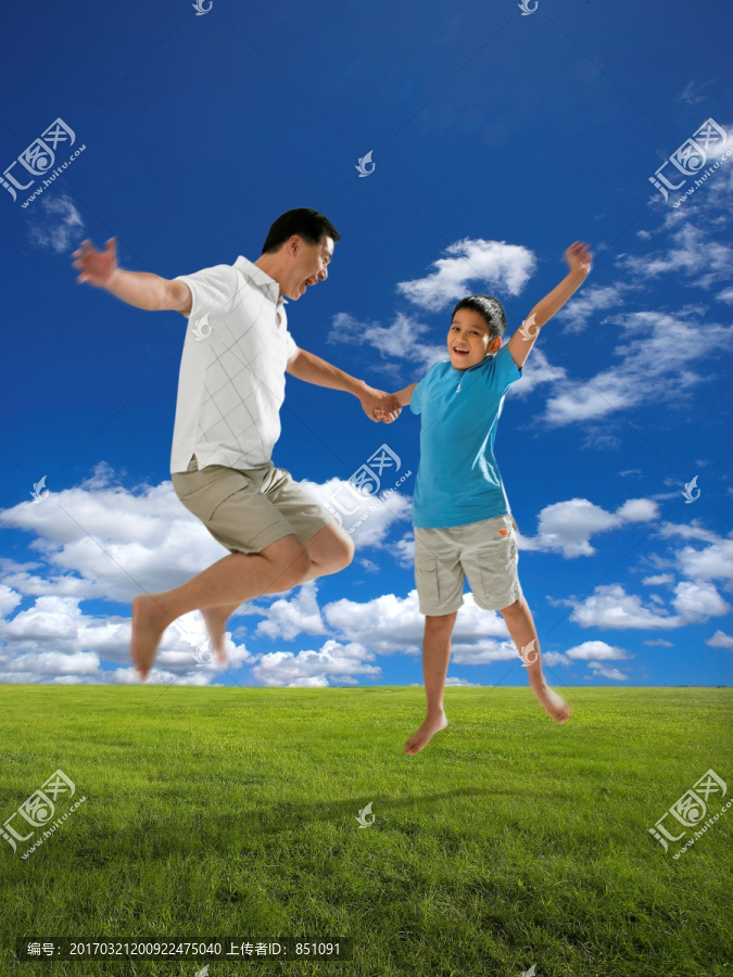 在草坪上跳跃的父子