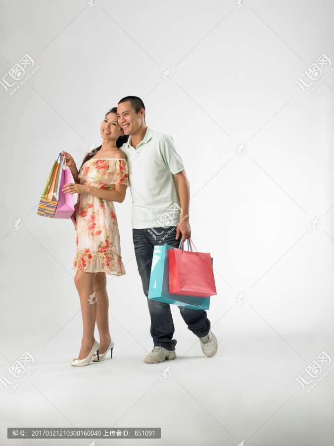 微笑着拎着购物袋的男女