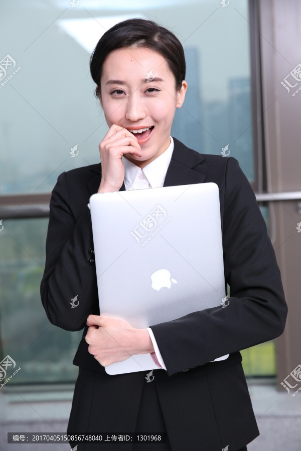 抱着笔记本电脑微笑着的女人
