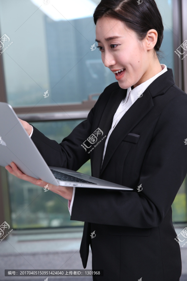 微笑着看着笔记本电脑的商务女士