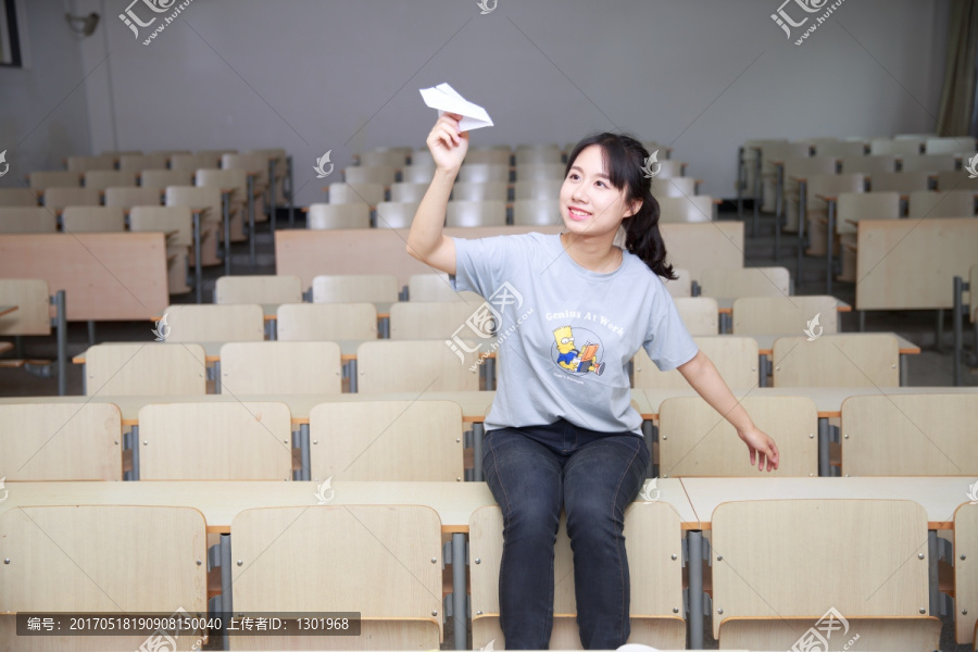 女大学生在大学教室里玩纸飞机