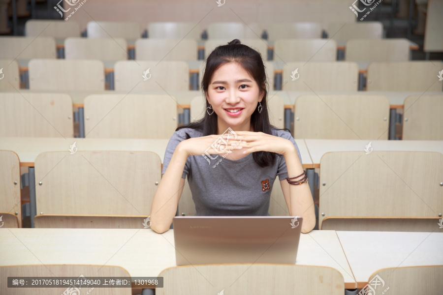 微笑的女学生坐在大学教室里