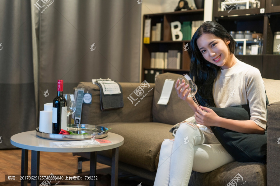 年轻女子坐在沙发上手拿红酒杯