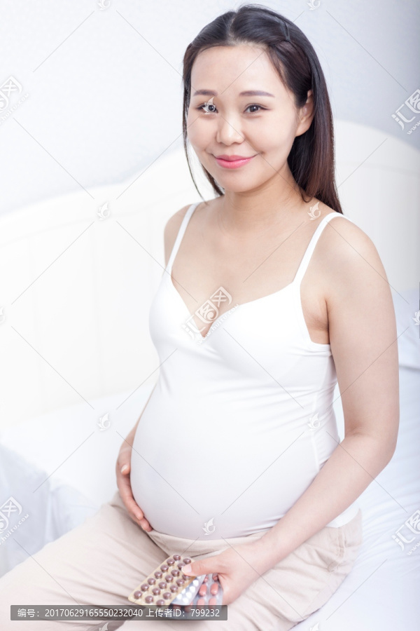 孕妇坐在床上手里拿着药丸