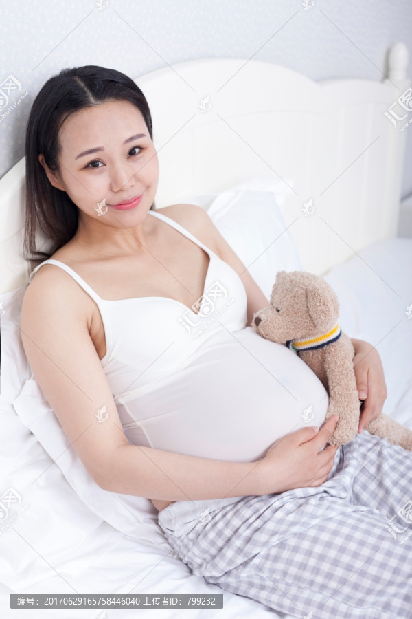 孕妇拿着毛绒玩具坐在床上