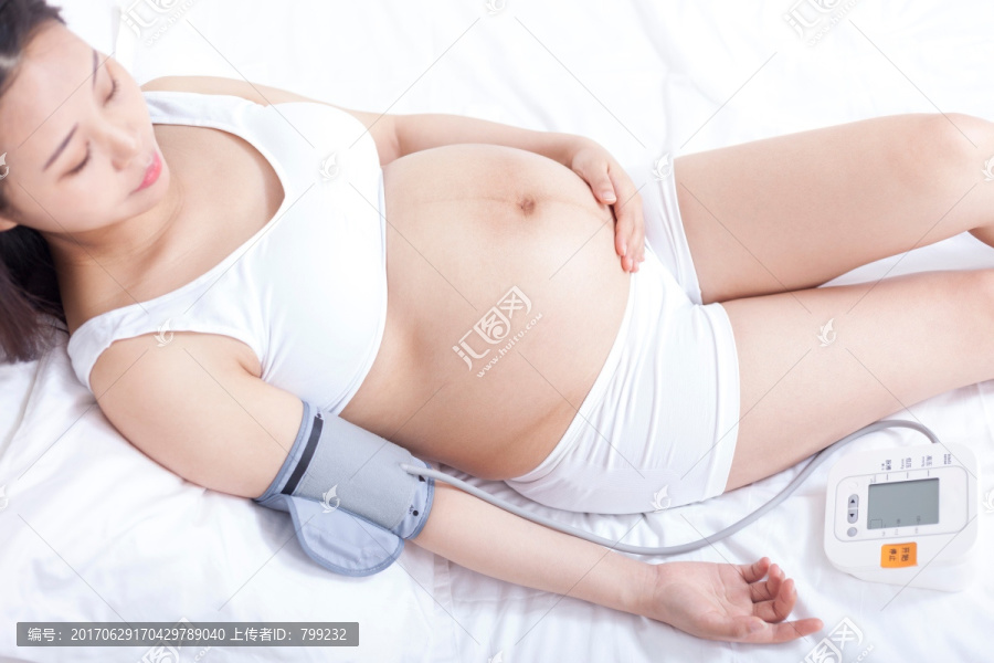 孕妇躺在床上检查血压