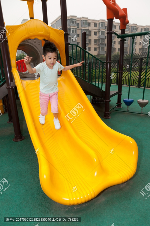 小男孩在幼儿园内玩滑梯