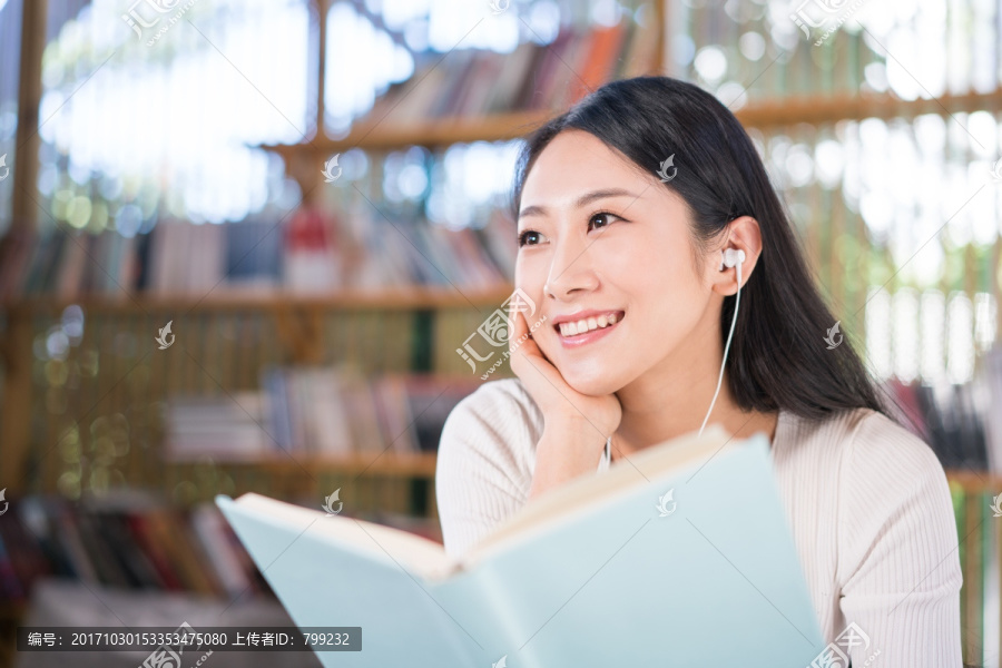 年轻女子在书店看书听音乐