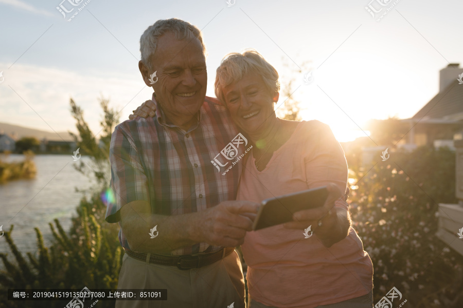 快乐的老年夫妇在后院用手机