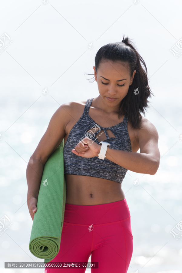 在海滩上使用智能手表的女人