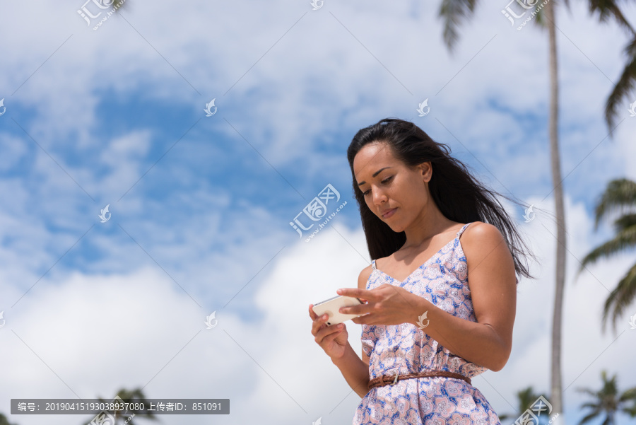 在海滩上使用手机的年轻女子
