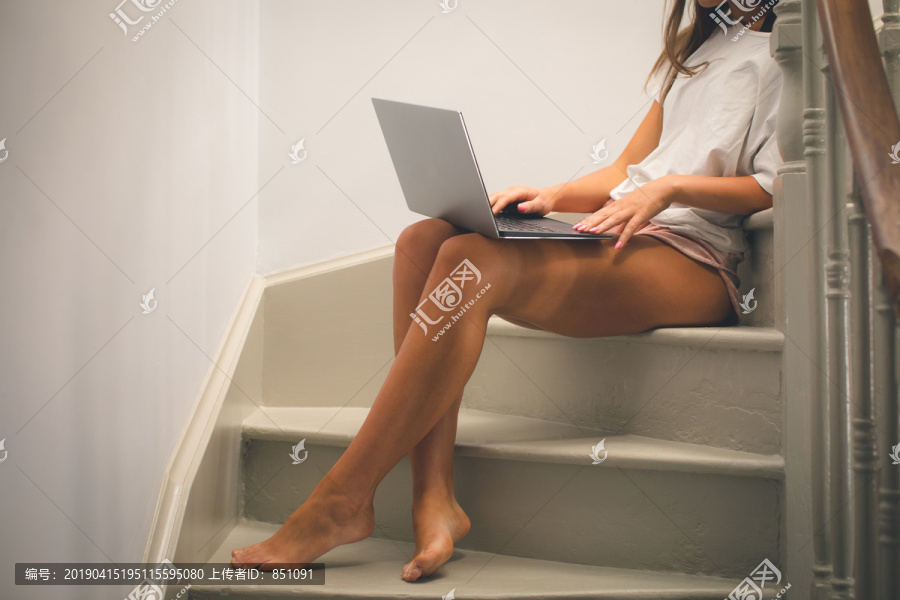 坐在楼梯上玩电脑的女人