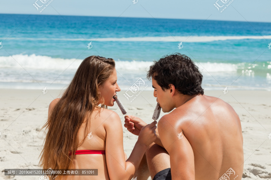 一对夫妇一起坐海边吃冰棒