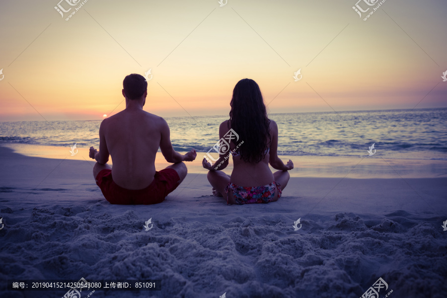 快乐的情侣在海边练瑜伽