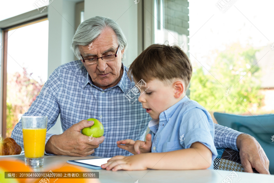 爷爷和孙子在餐桌上用平板电脑