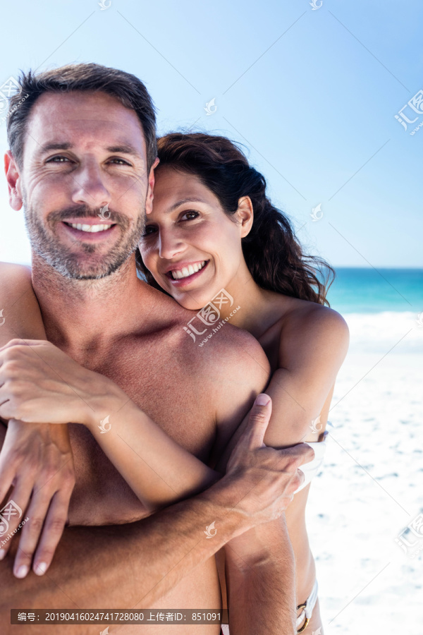 可爱的情侣在海滩上搂着胳膊