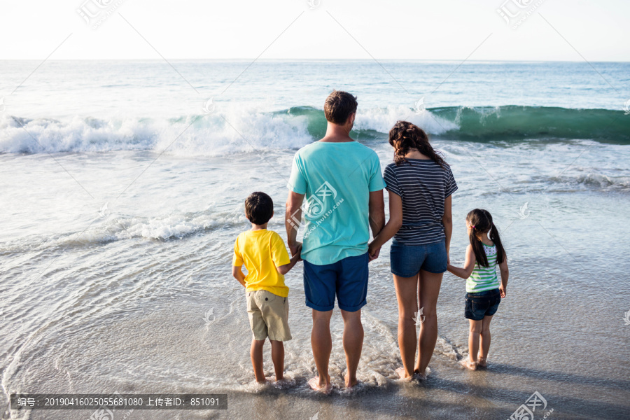 一家人站在沙滩上的水里