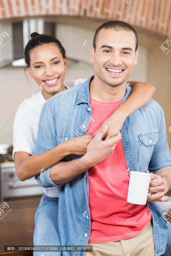 一对微笑的夫妇在家里的厨房拥抱