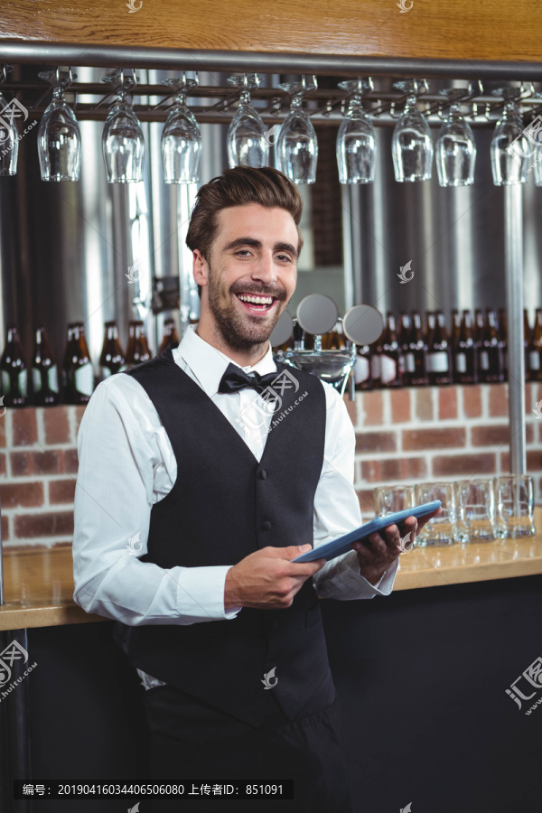 酒吧男招待在酒吧里用平板电脑