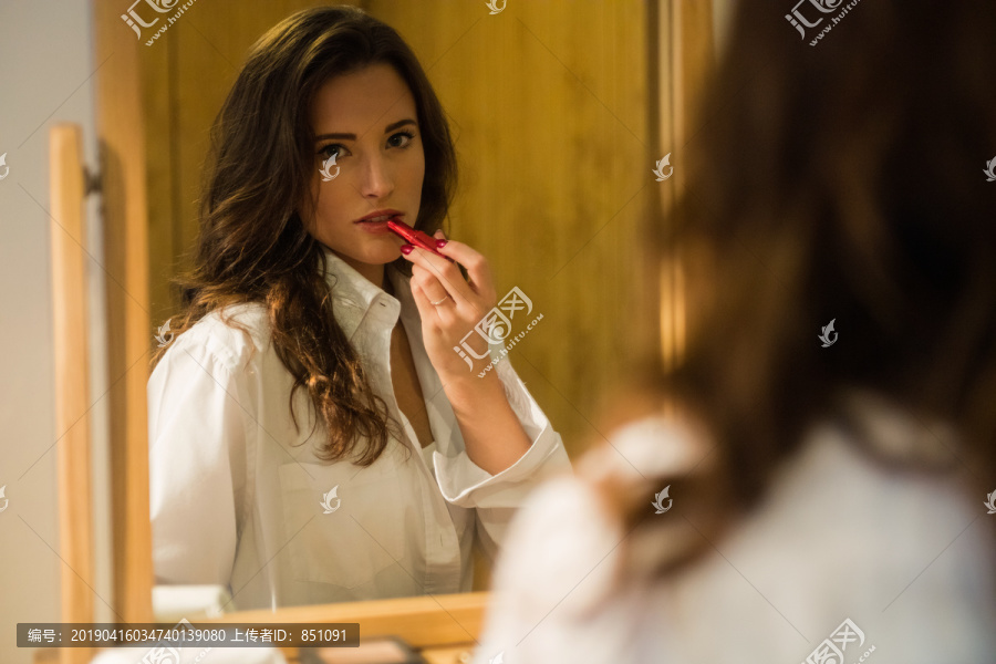 黑发女人在镜子前涂口红