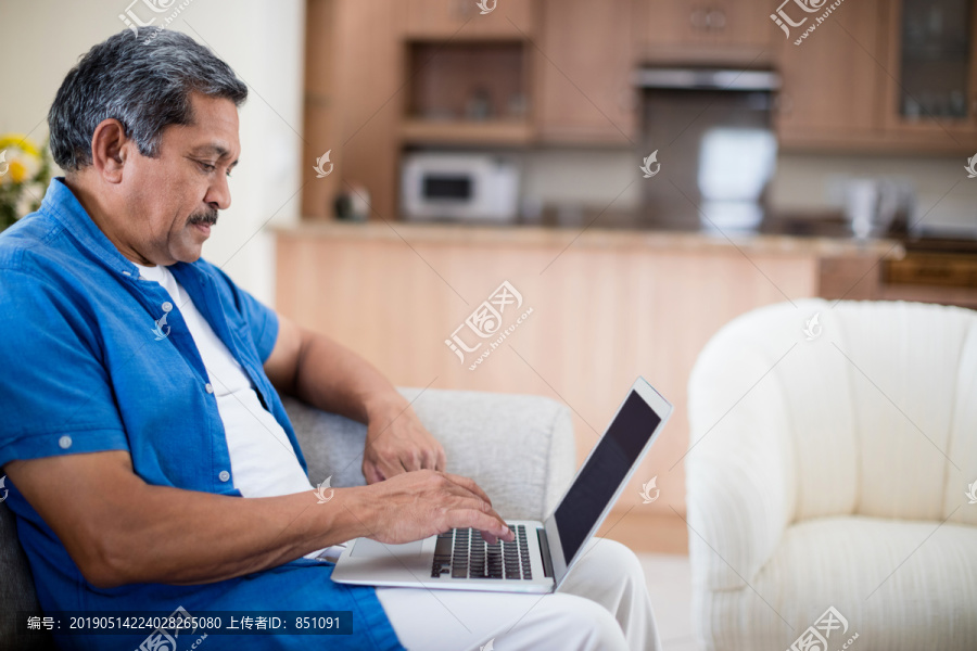 在客厅使用笔记本电脑的老人