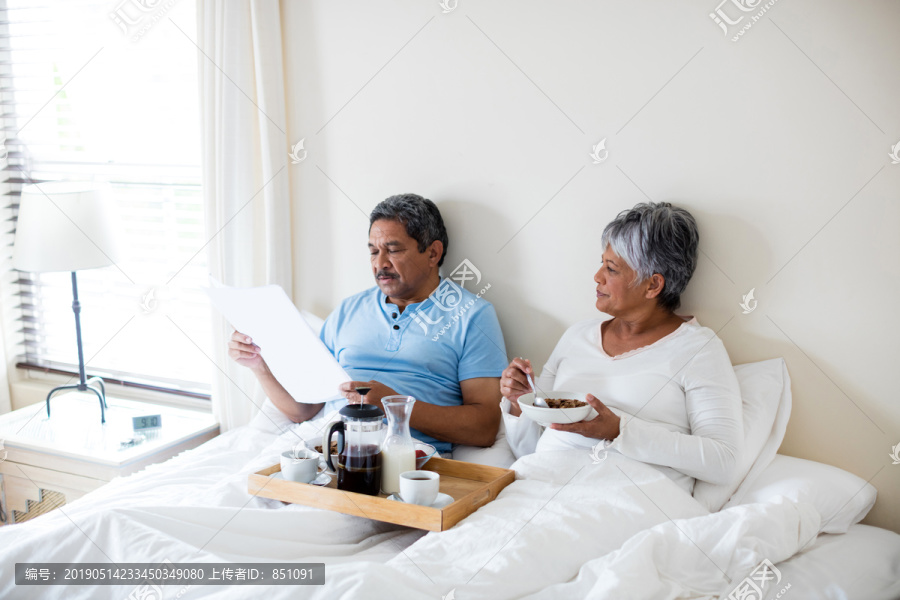 老年夫妇在家里卧室吃早餐