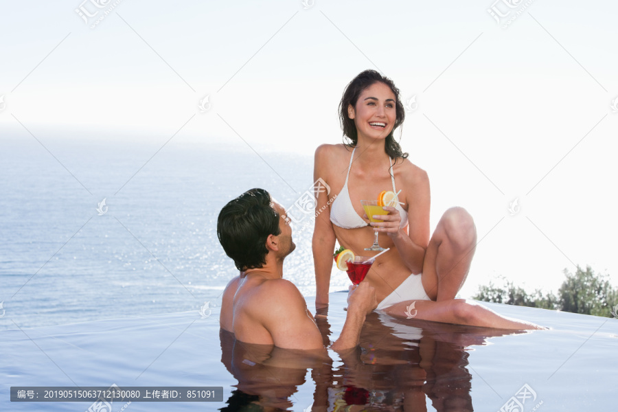 坐在泳池边微笑的夫妇